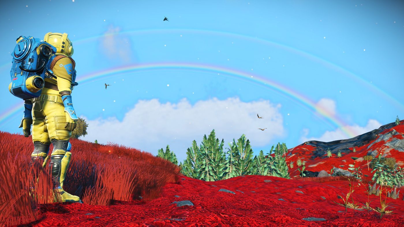 No Man's Sky: an astronaut in a yellow suit with a blue backpack in red grass under a rainbow