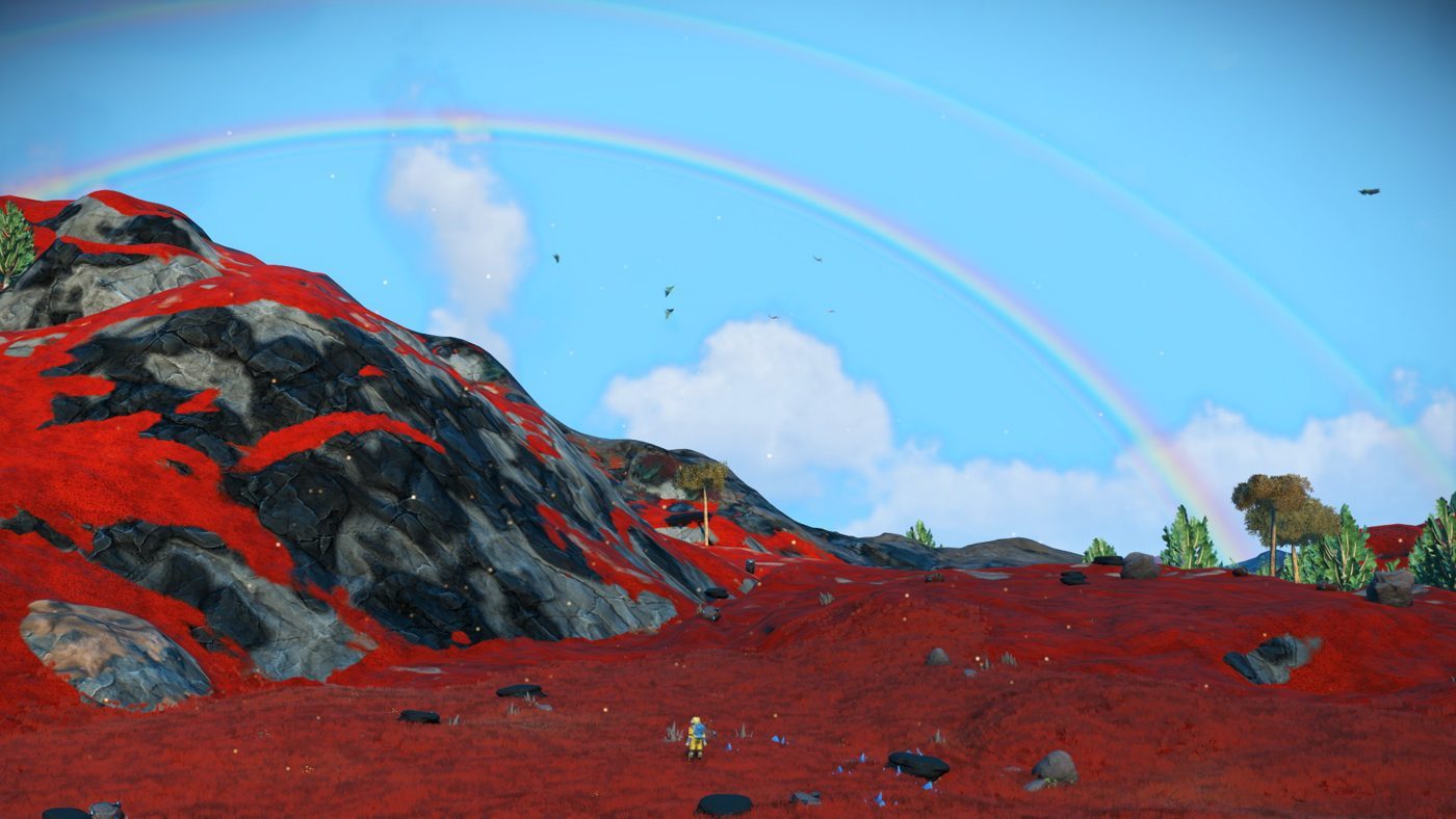 No Man's Sky: a double rainbow over red hills with a tiny astronaut in the distance